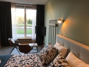 a bedroom with a bed and a chair and a window at De Kade in Groningen