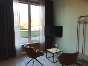 een hotelkamer met 2 stoelen, een tafel en een televisie bij De Kade in Groningen