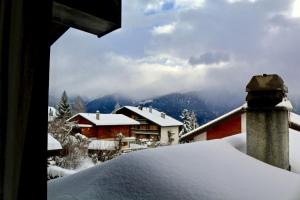 a house covered in snow with mountains in the background at Au centre d'Ovronnaz - Chalet mitoyen in Ovronnaz