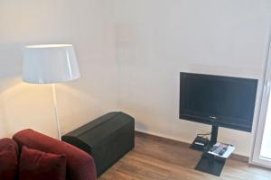 a living room with a tv and a chair and a lamp at Au centre d'Ovronnaz - Chalet mitoyen in Ovronnaz