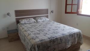 Schlafzimmer mit einem Bett mit einer weißen und blauen Bettdecke in der Unterkunft Maravilhosa Villa com Piscina in Arraial do Cabo + 65 Fotos