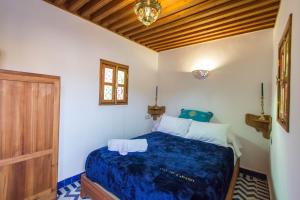 1 dormitorio con cama con sábanas azules y techo de madera en Dar Mfaddel, en Fez