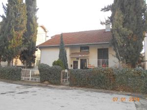 ein weißes Haus mit einem Zaun und Bäumen in der Unterkunft Atocha in Skopje
