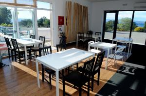 a dining room with tables and chairs and windows at Hostel Dharma in Rijeka