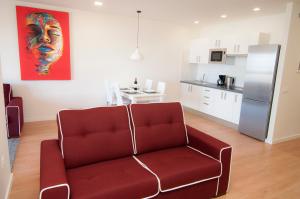 a living room with a red couch and a kitchen at Los Rodeos Luxury Vivienda Vacacional in La Laguna