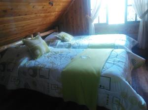 a bedroom with two beds with white blankets and pillows at Cabañas Típicas ARIAS in Oxapampa