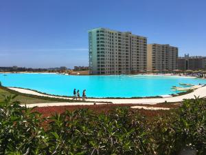 uma grande piscina de água azul com edifícios ao fundo em Departamento en Laguna Bahia em Algarrobo