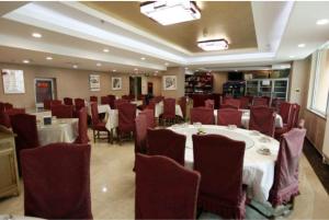 uma sala de jantar com mesas brancas e cadeiras vermelhas em GreenTree Inn Beijing Shunyi Xinguozhan Express Hotel em Shunyi