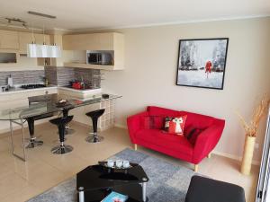 a living room with a red couch and a kitchen at Departamento Laguna Bahia Algarrobo in Algarrobo