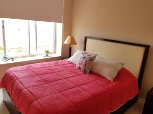 a bedroom with a large red bed with two pillows at Departamento Laguna Bahia Algarrobo in Algarrobo +36 photos