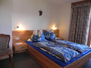 ウッテンドルフにあるBauernhof Fuchsmoosのベッドルーム1室(青い掛け布団、椅子付)