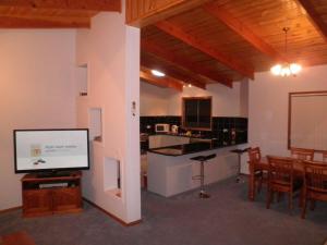 a living room with a flat screen tv and a kitchen at The Real McCoy Holiday Accommodation in Broken Hill