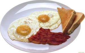 two eggs and bacon on a plate with toast at Sascha's Resort Oslob in Oslob