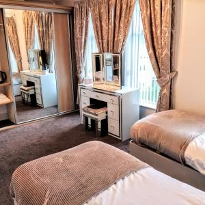 a bedroom with two beds and a dresser with a mirror at Number 43 in Derry Londonderry