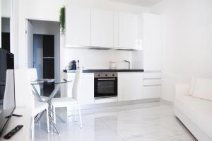 a white kitchen with white cabinets and a table at Maison Audrey in Desenzano del Garda