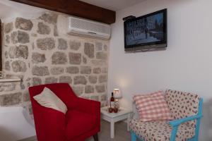 a living room with a red chair and a tv at Apartment Stulli 1 in Dubrovnik