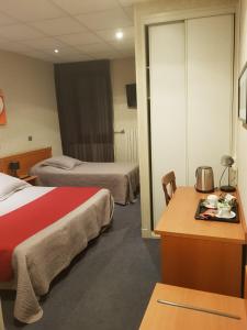 a hotel room with two beds and a desk at Hôtel de l'Europe in Saint-Jean-de-Maurienne