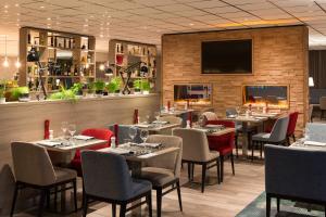 فندق مركيور أمستردام ويست في أمستردام: مطعم بطاولات وكراسي وتلفزيون بشاشة مسطحة