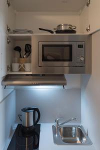 a kitchen with a microwave above a kitchen counter at FirstSleep Boardinghouse Griesfeldstrasse München in Munich