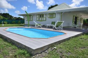 a swimming pool in front of a house at Residence Clementine villa Douceur in Grand-Bourg