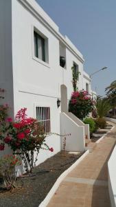 a white building with flowers in front of it at Apartment Enjoy Corralejo in Corralejo