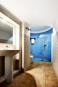 La salle de bains est pourvue d'un lavabo et d'une douche avec du carrelage bleu. dans l'établissement Hotel Ahc Palacio Coria, à Coria