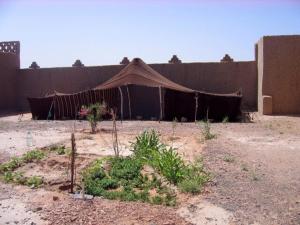 a tent in front of a building with plants at Tazoult Ouzina in Ouzina