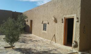 - un bâtiment avec une porte et un arbre à côté dans l'établissement Tazoult Ouzina, à Ouzina