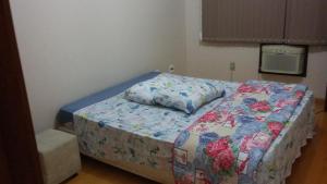 a small bedroom with a bed with a floral comforter at Sobrado EXPRESS - Santa Cruz do Sul! in Santa Cruz do Sul