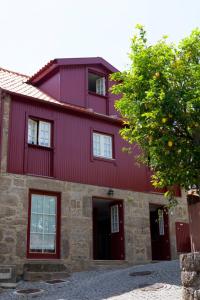 una casa roja con un árbol delante en Casa da Obrinha, en Bouro