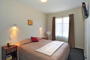 1 dormitorio con 1 cama grande y TV en 540 on Great South Motel, en Auckland