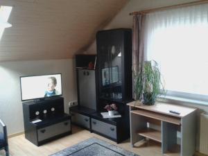 sala de estar con TV y escritorio en Ferienwohnung Bäumener en Hilchenbach