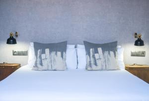 Una cama con sábanas blancas y almohadas en un dormitorio en The Lights City Rooms, en Málaga
