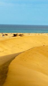 a beach with a group of people in the ocean at Casa Toni e Inma in Maspalomas