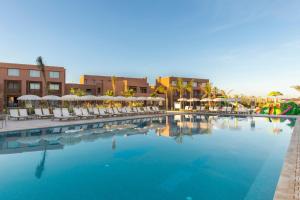 a large swimming pool with chairs and umbrellas at Be Live Experience Marrakech Palmeraie - All Inclusive in Marrakech