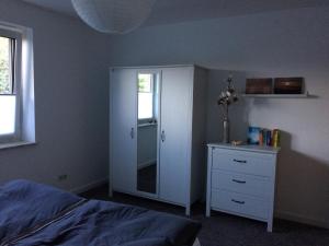 a bedroom with a bed and a dresser and a mirror at Strandstern mit Wallbox in Wremen