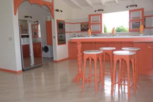 a kitchen with wooden stools and a counter in a kitchen at Résidence Clémentine Villa Passion in Grand-Bourg