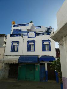a tall white building with blue windows and a green door at Pilar Ruiz in Asilah