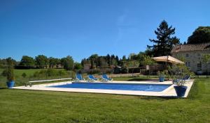 einen Pool in einem Garten mit Stühlen und einem Sonnenschirm in der Unterkunft La Bucherie in Montembœuf