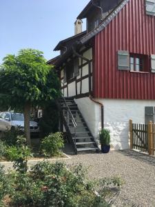 un edificio rojo y blanco con escaleras junto a un árbol en Ferienwohnung Hornauer, en Salem