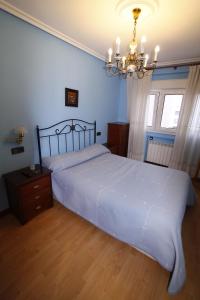 Un dormitorio con una cama grande y una lámpara de araña. en Apartamento con encanto y vistas en playa San Lorenzo, en Gijón
