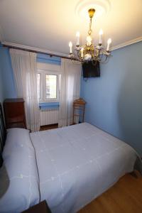 una camera da letto con un grande letto bianco e un lampadario a braccio di Apartamento con encanto y vistas en playa San Lorenzo a Gijón