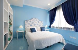 a blue bedroom with a white bed and a window at Hotel Bougainville in Positano