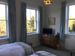 Un dormitorio con una cama y un televisor y ventanas. en Grosmont House, en Grosmont