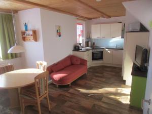 sala de estar con sofá rojo y cocina en Casa Emmi, en Bad Mitterndorf