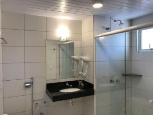 a bathroom with a sink and a shower with a mirror at Hotel Villa das Termas Machadinho in Machadinho