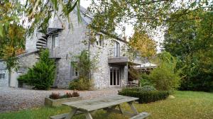 a wooden picnic table in front of a stone house at Gite Saboti in Dinant