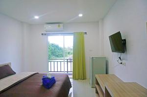 a bedroom with a bed and a window with a television at A.D. Living in Hua Hin