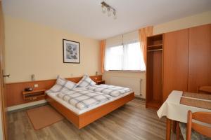 a bedroom with a bed and a table and a window at Weingut***Pension Günther Scholtes in Leiwen