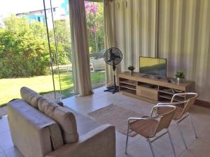 sala de estar con sofá, sillas y TV en CASA 100 MTS DA PRAIA!, en Florianópolis